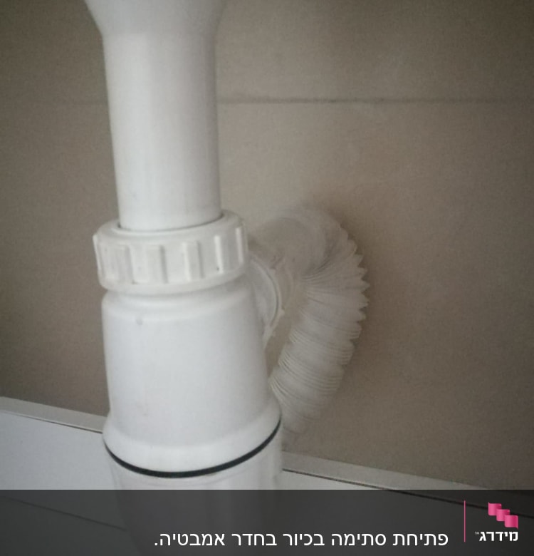 צינור ניקוז לבן מתחת לכיור עם חיבור גמיש